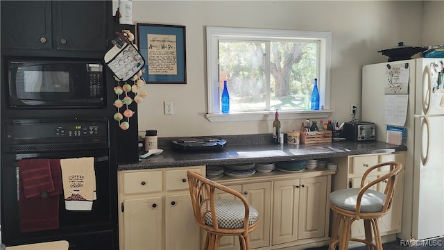 kitchen featuring cream cabinetry and black appliances