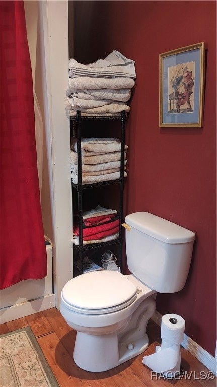 bathroom with toilet and wood-type flooring