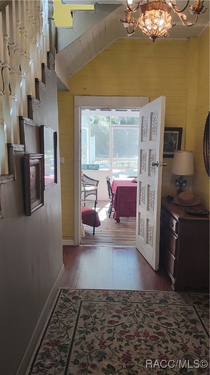 hallway featuring hardwood / wood-style flooring, vaulted ceiling, and a notable chandelier