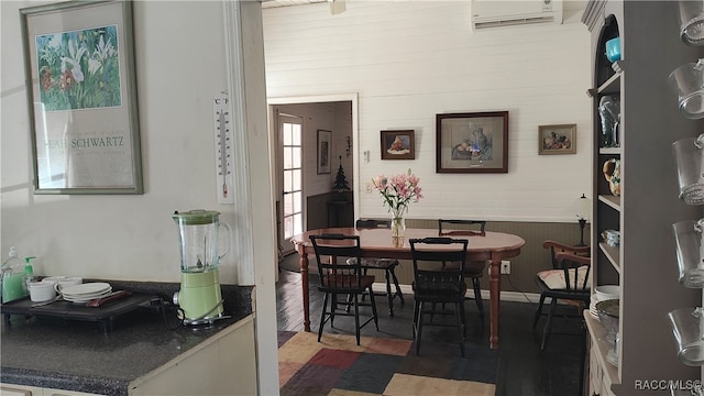 dining space with an AC wall unit, dark wood-type flooring, and wooden walls