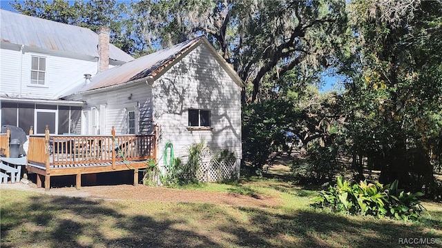 rear view of house featuring a sunroom, a deck, and a yard