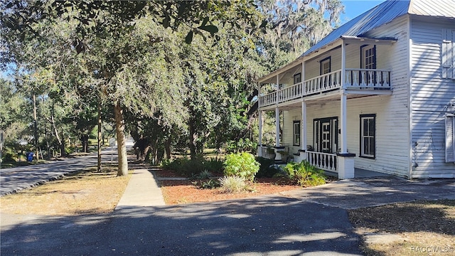 view of side of property with covered porch and a balcony