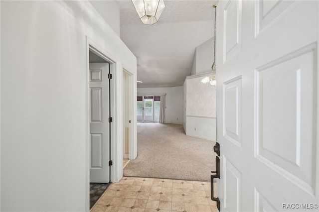 hall featuring light carpet and a notable chandelier