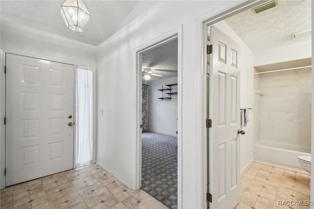 foyer entrance with ceiling fan and a textured ceiling