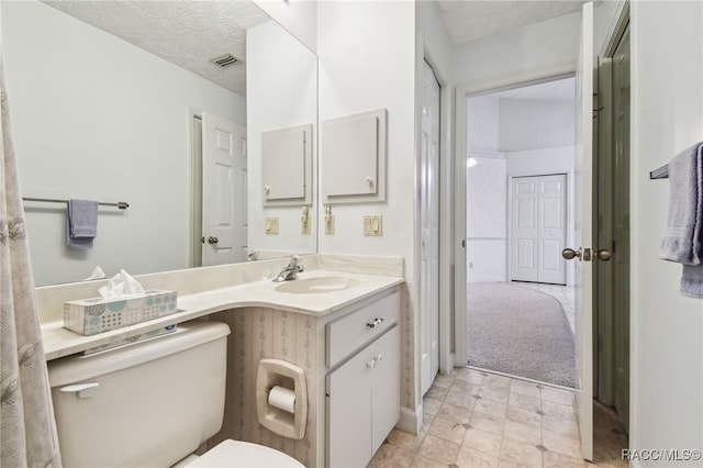 bathroom featuring vanity, a textured ceiling, and toilet