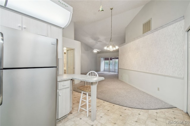 kitchen featuring light carpet, a kitchen breakfast bar, pendant lighting, a notable chandelier, and stainless steel refrigerator