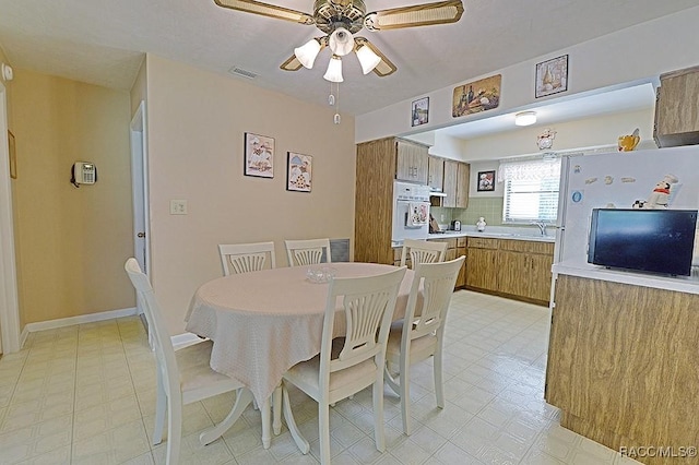 dining room featuring a ceiling fan, baseboards, visible vents, and light floors