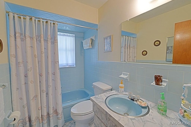 full bathroom featuring a wainscoted wall, tile walls, toilet, shower / bath combo with shower curtain, and a sink