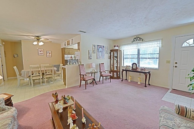 living area featuring light carpet, visible vents, a textured ceiling, and light tile patterned floors