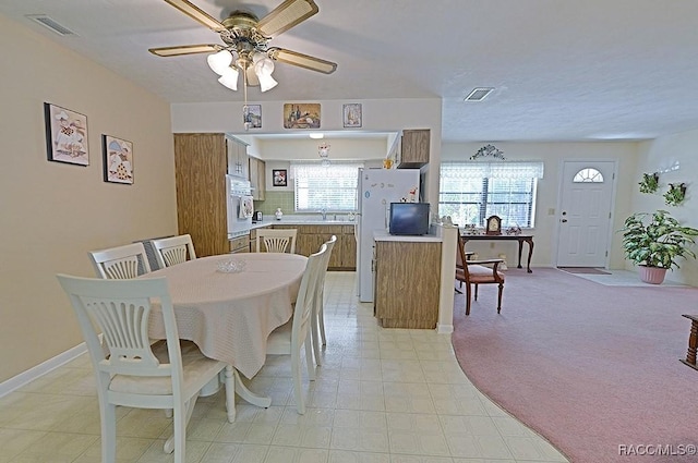 dining space featuring ceiling fan, baseboards, visible vents, and light colored carpet