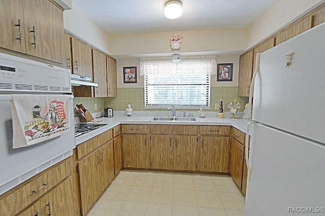 kitchen featuring white appliances, backsplash, light countertops, under cabinet range hood, and a sink