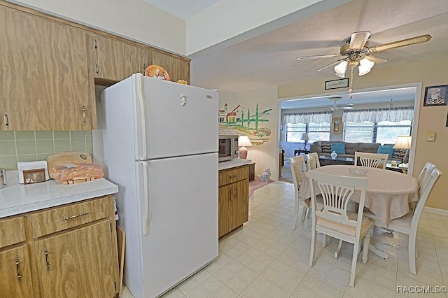 kitchen featuring a ceiling fan, light countertops, backsplash, freestanding refrigerator, and brown cabinets