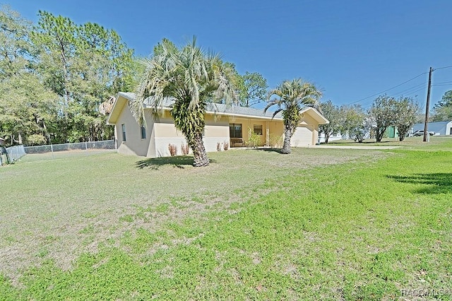 exterior space with an attached garage, fence, a lawn, and stucco siding