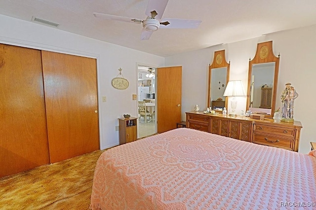 bedroom with a closet, visible vents, ceiling fan, and light carpet