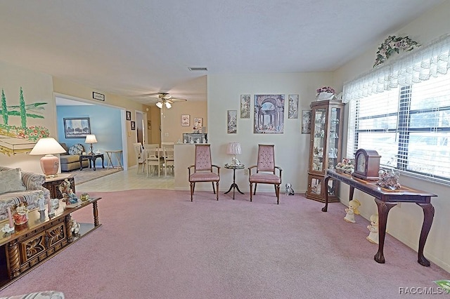 living area with light carpet, ceiling fan, visible vents, and baseboards