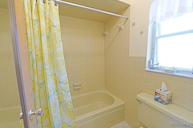 bathroom with toilet, shower / bath combination with curtain, and tile walls