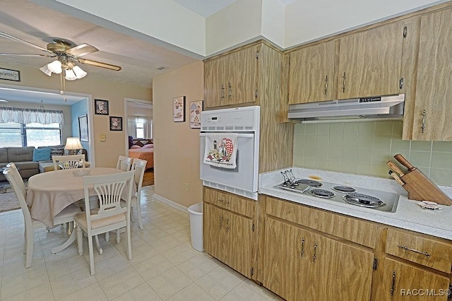 kitchen with ceiling fan, under cabinet range hood, white appliances, light countertops, and decorative backsplash