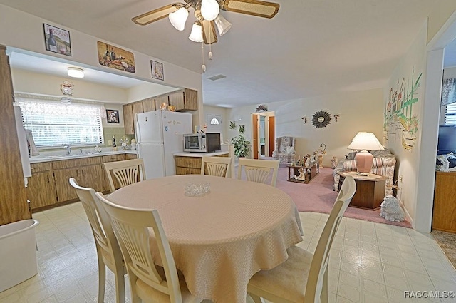 dining area with ceiling fan, light floors, and visible vents