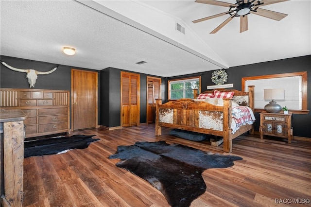 bedroom featuring ceiling fan, dark hardwood / wood-style flooring, vaulted ceiling, and a textured ceiling