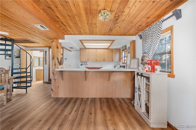 kitchen featuring light brown cabinetry, a breakfast bar area, light hardwood / wood-style flooring, wooden ceiling, and kitchen peninsula