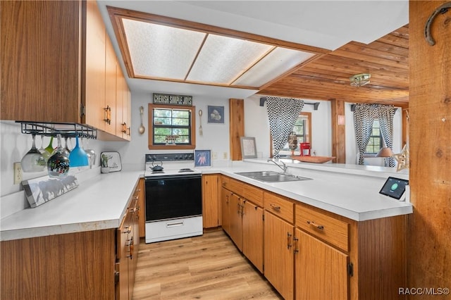 kitchen featuring sink, electric range, light hardwood / wood-style flooring, and kitchen peninsula