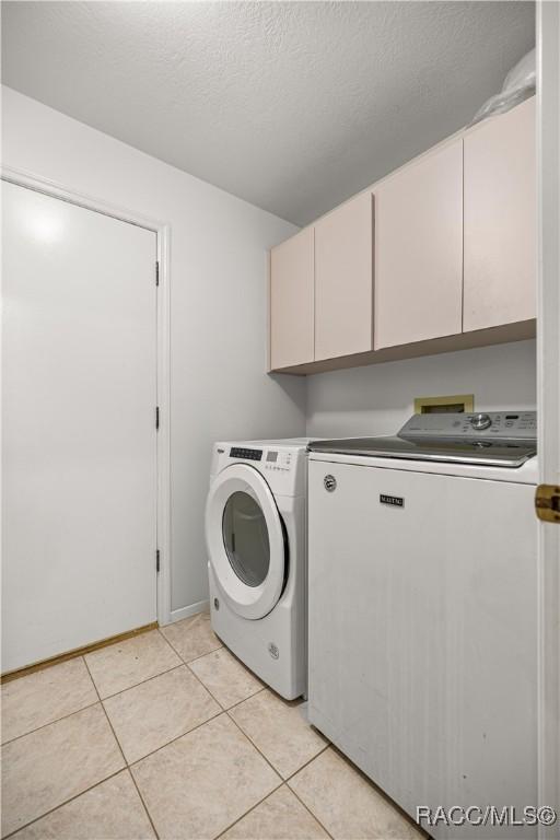 9530 SW 189th Ct, Dunnellon, FL 34432 - laundry area with cabinet space, washer and clothes dryer, light tile patterned floors, a textured ceiling, and baseboards