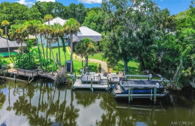 view of dock with glass enclosure, a water view, and a yard