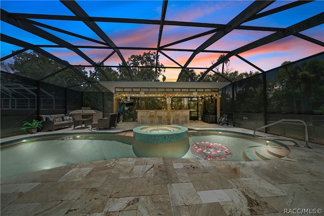 pool at dusk with glass enclosure, an outdoor bar, an outdoor hangout area, and a patio