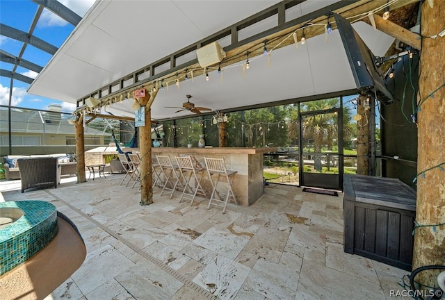 view of patio / terrace with ceiling fan, an outdoor bar, and glass enclosure