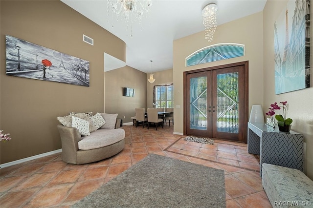 tiled entrance foyer with french doors, high vaulted ceiling, and a chandelier