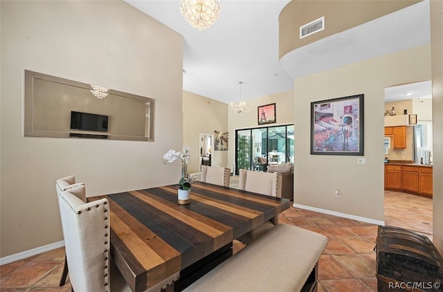 dining space featuring a towering ceiling, light tile patterned floors, and a notable chandelier