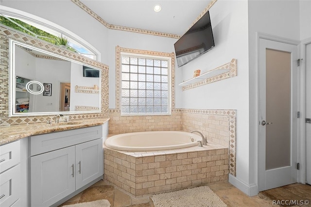 bathroom featuring vanity, a wealth of natural light, and tiled tub