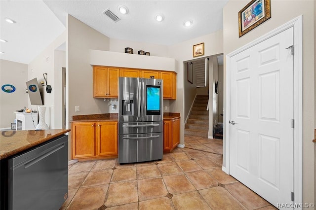 kitchen with appliances with stainless steel finishes, light tile patterned floors, and dark stone counters