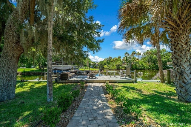 surrounding community featuring a boat dock, a water view, and a lawn