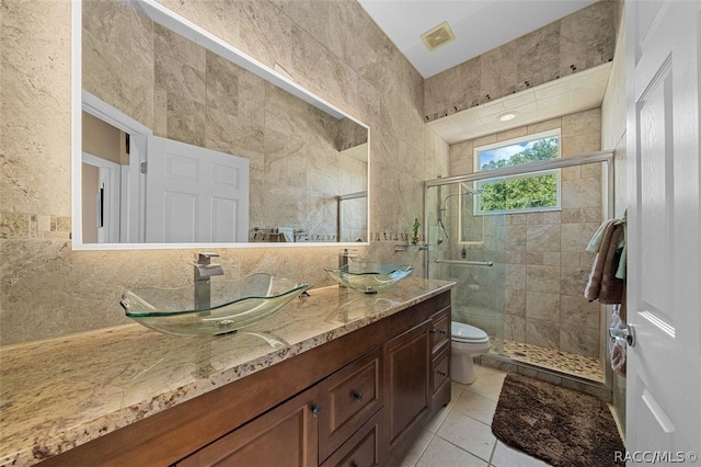 bathroom featuring tile patterned floors, vanity, tile walls, toilet, and a shower with shower door