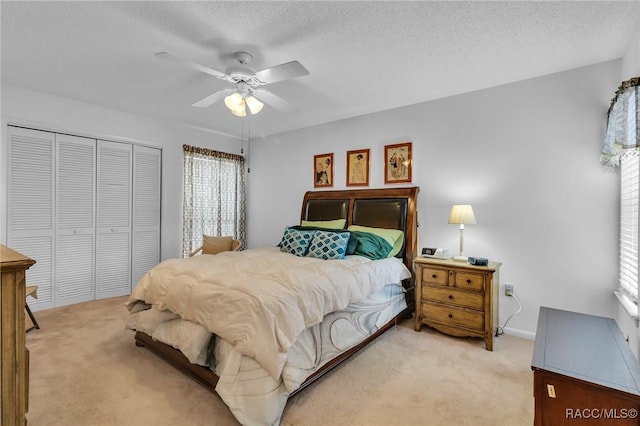 bedroom featuring light carpet, a textured ceiling, a closet, and ceiling fan