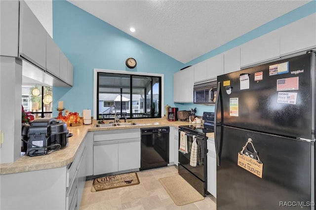 kitchen featuring black appliances, white cabinetry, lofted ceiling, and sink