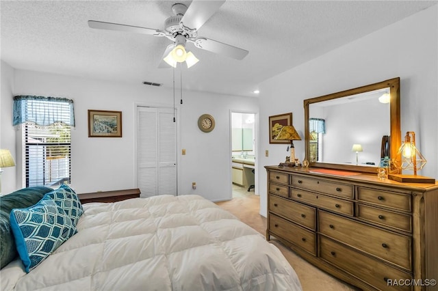 bedroom with light carpet, ensuite bathroom, a textured ceiling, ceiling fan, and a closet