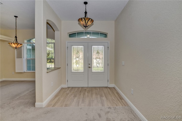 entryway with light colored carpet, a wealth of natural light, and french doors