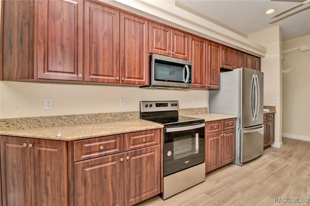 kitchen with light stone counters, light hardwood / wood-style flooring, ceiling fan, and stainless steel appliances