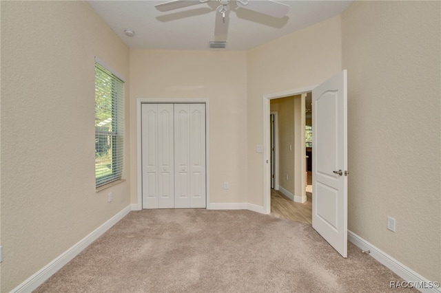 unfurnished bedroom with ceiling fan, light carpet, and a closet