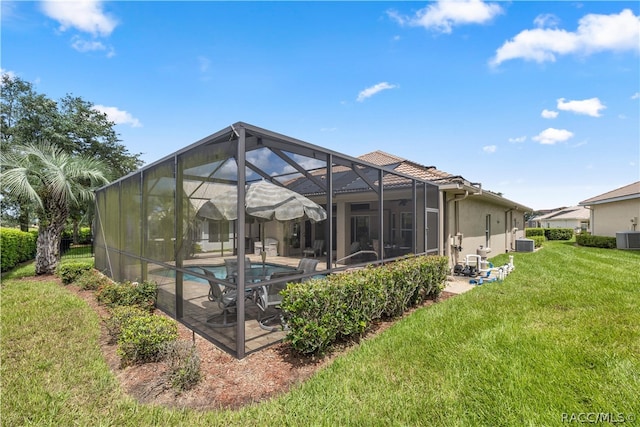 back of property featuring a lanai, central air condition unit, a lawn, and a patio