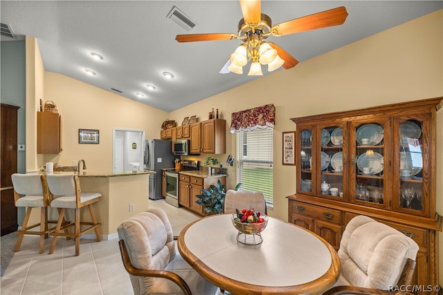 tiled dining space with ceiling fan, lofted ceiling, and sink