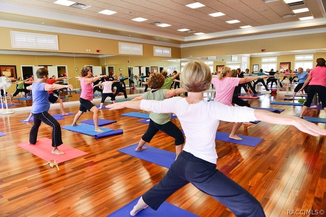 gym with light hardwood / wood-style floors and ornamental molding