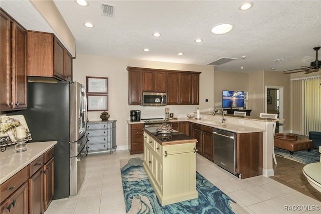 kitchen featuring sink, kitchen peninsula, stainless steel appliances, and light tile patterned floors