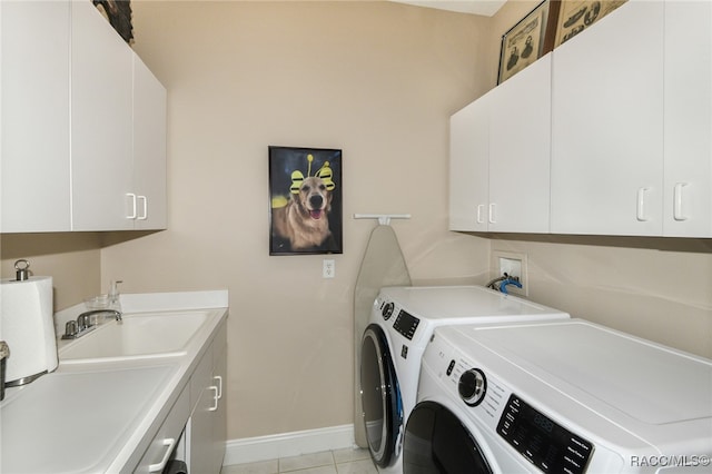 washroom with cabinets, light tile patterned floors, washing machine and dryer, and sink