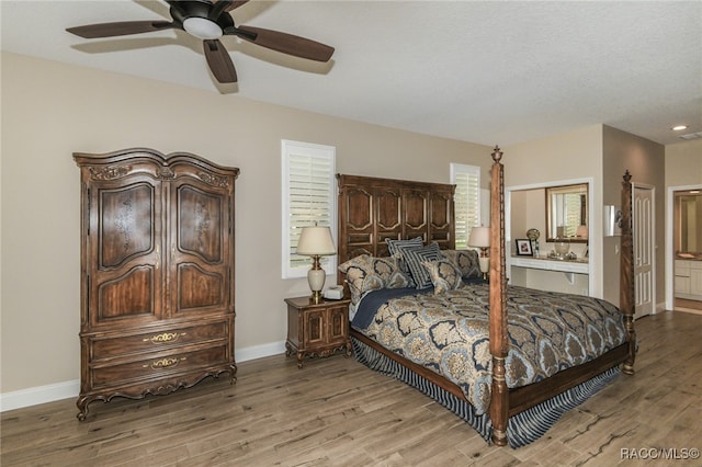 bedroom featuring ceiling fan, light hardwood / wood-style floors, multiple windows, and ensuite bath