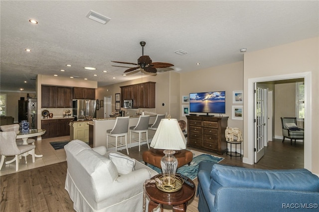 living room featuring a textured ceiling, ceiling fan, and dark wood-type flooring