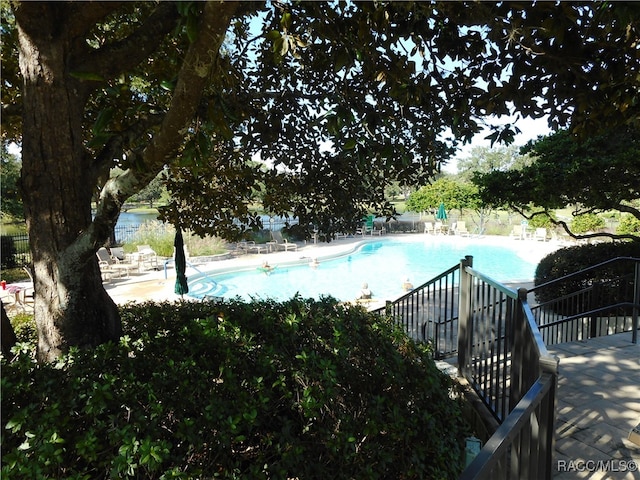 view of swimming pool featuring a water view and a patio