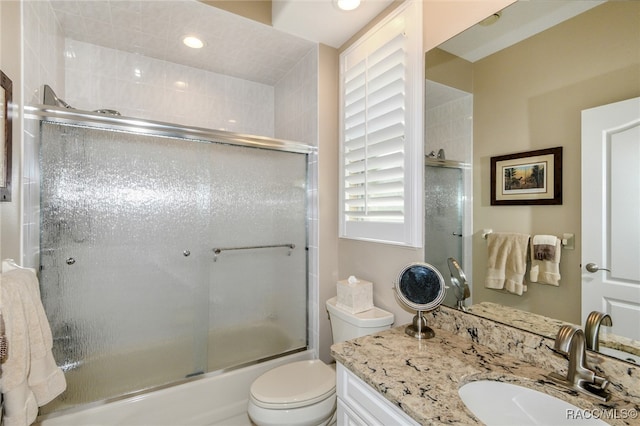 full bathroom with vanity, combined bath / shower with glass door, and toilet